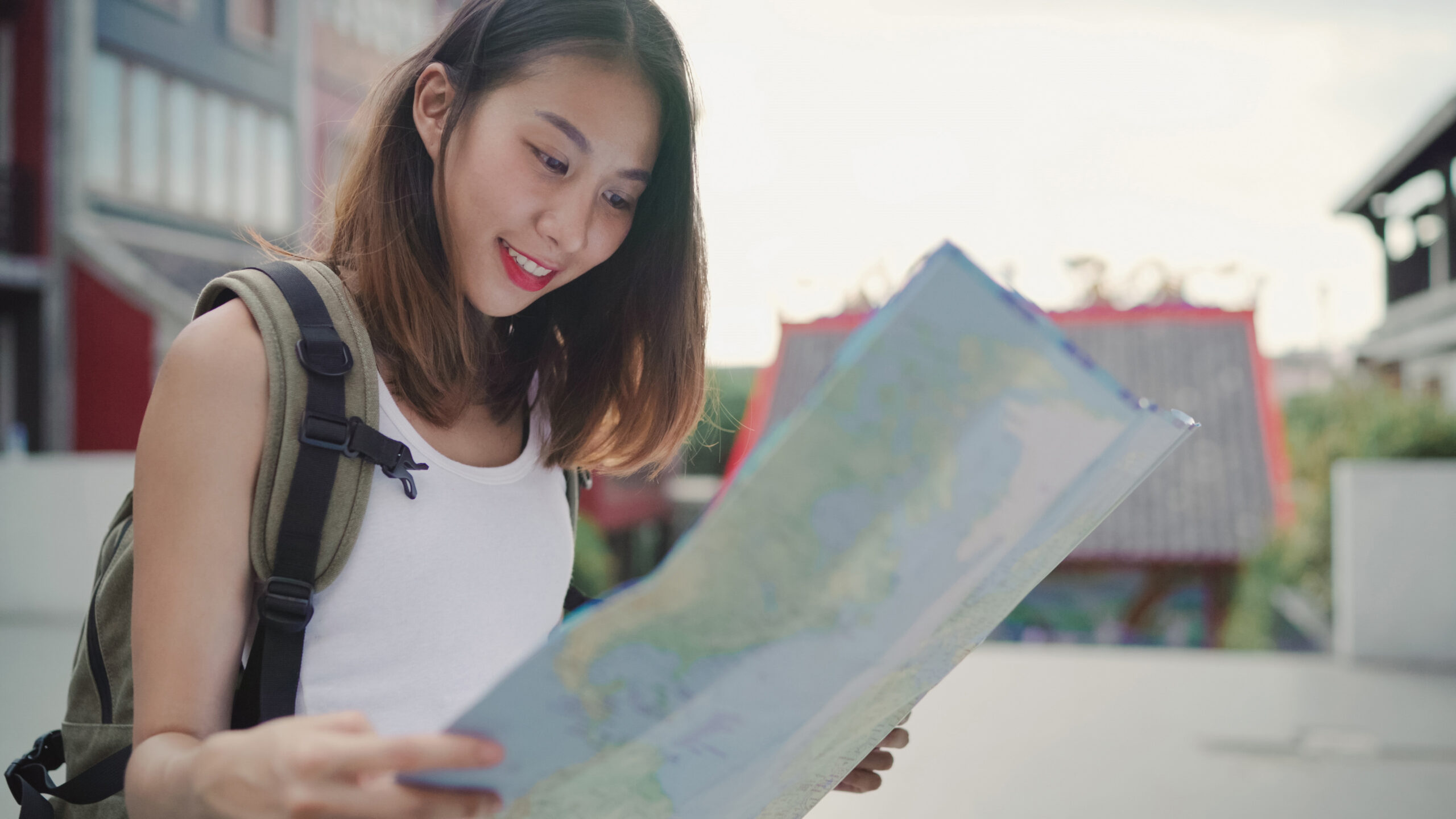 Cheerful beautiful young Asian backpacker woman direction and looking on location map while traveling at Chinatown in Beijing, China. Lifestyle backpack tourist travel holiday concept.